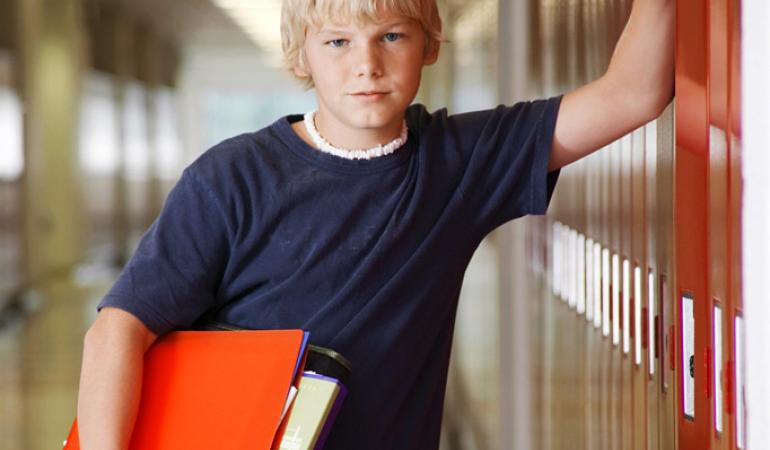 tiener jongen met ordner onder zijn arm bij schoolkluisje